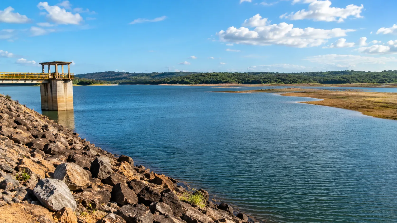 Ilustração editorial panorâmica de reservatório com água azul, margem de pedras, faixas de terra expostas e estrutura de captação ao lado esquerdo.