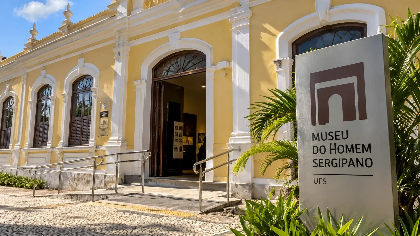 Ilustração digital de fachada amarela com ornamentos brancos e placa alusiva ao Museu do Homem Sergipano.